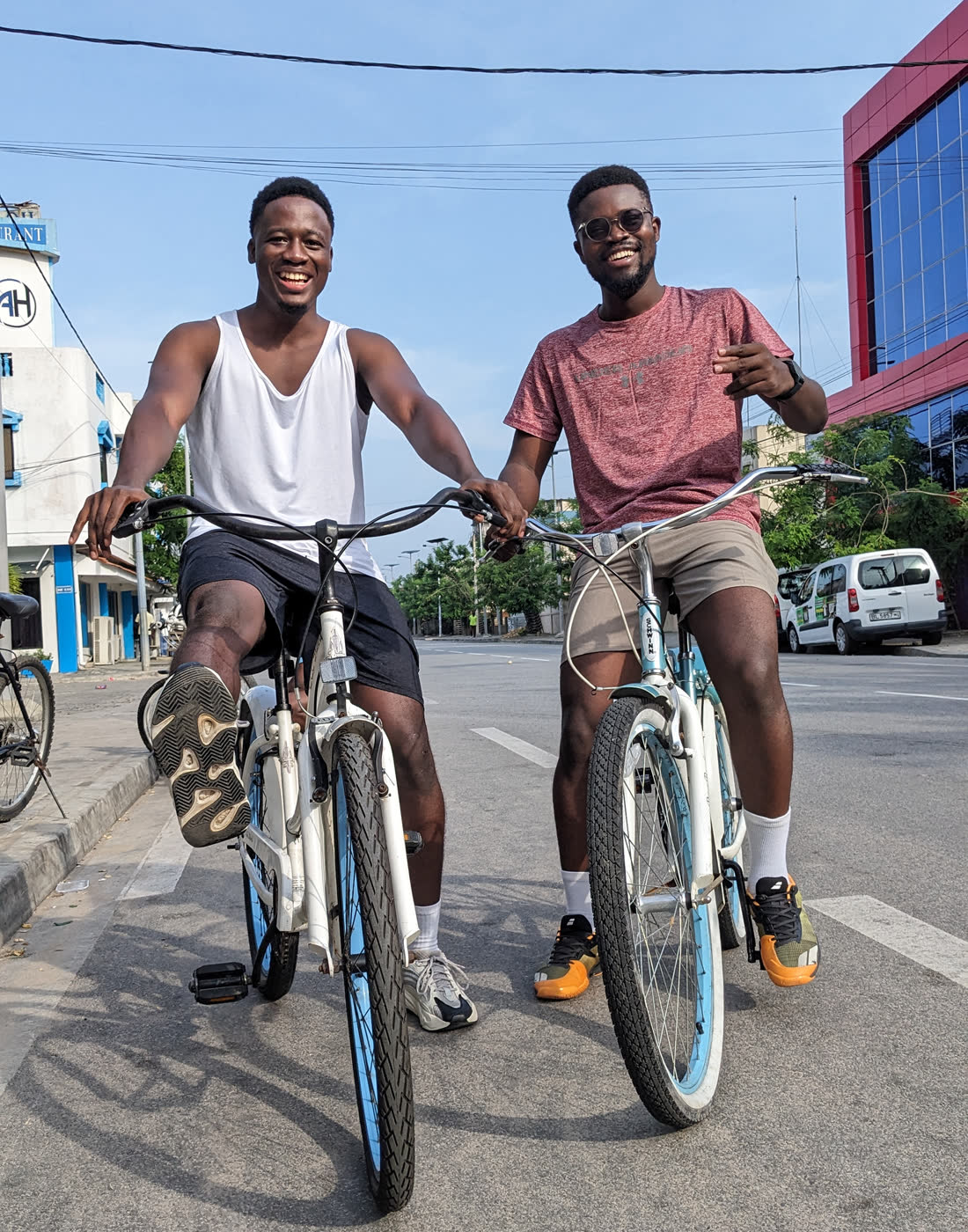 Deux clients Koin Koin Vélo sur leurs vélos dans une rue de Cotonou